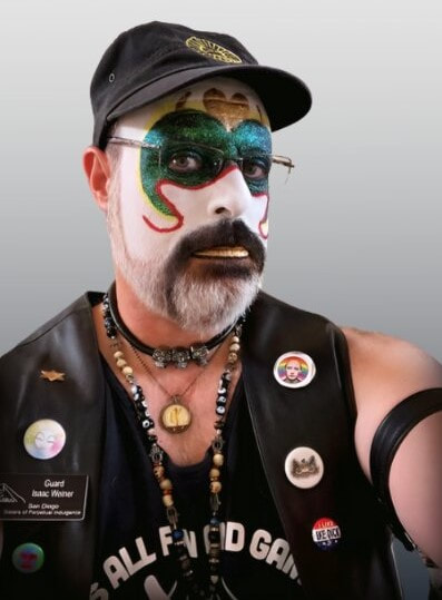 Guard Isaac Weiner of The San Diego Sisters of Perpetual Indulgence in clown-white and green glitter makeup, wearing a black baseball cap.