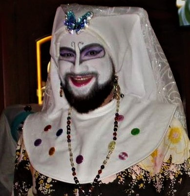 Novice Sister Gwenn N. Dowtte of The San Diego Sisters of Perpetual Indulgence in clown white with purple butterfly inspired makeup and wearing white veils.