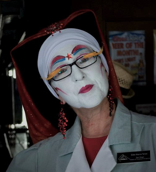 Sister Bianca Tempt of The San Diego Sisters of Perpetual Indulgence in clown white and red and blue makeup wearing red veils and glashes.